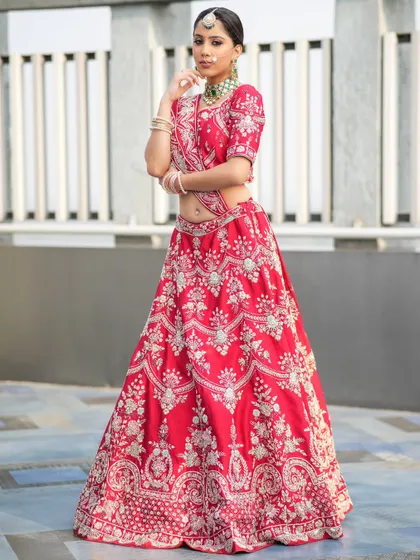 A full-length view of a stunning bridal look. This heavily embroidered red lehenga is perfectly accessorized with our green-accented choker, maang tikka, and bangles, showing how our jewellery completes your entire wedding day vision.