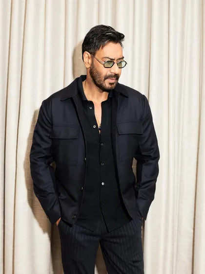 Ajay Devgn looking sharp in a layered all-black look for the 'Shaitaan' premiere, with green-tinted glasses adding a modern twist.