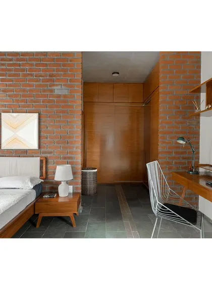 We used exposed brick and warm wood tones in the master bedroom to create a cozy and rustic feel. The space includes a dedicated study nook, showing how we integrate practical functions into our designs without compromising on style.