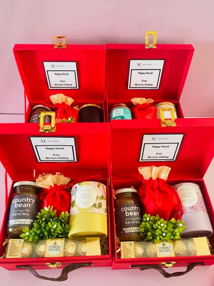 A look at a bulk order of our customized red suitcase hampers, each filled with items like Country Bean coffee, Ferrero Rocher, and scented candles.