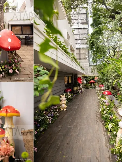 An enchanting pathway for a woodland-themed event. Guests are greeted by friendly rabbit statues and whimsical mushroom props nestled among flowers, leading them into a magical forest setting.