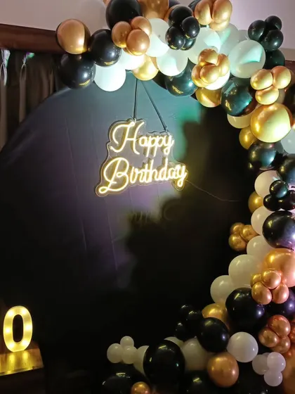 A close-up of the elegant 60th birthday balloon arch, showing the mix of black, white, and chrome gold balloons.