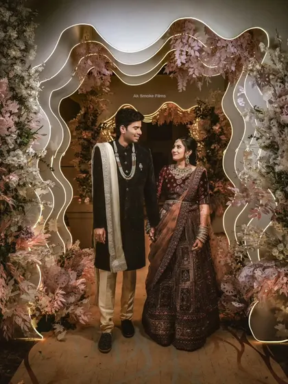 A full-length shot of the couple walking through the beautiful, illuminated floral arch.