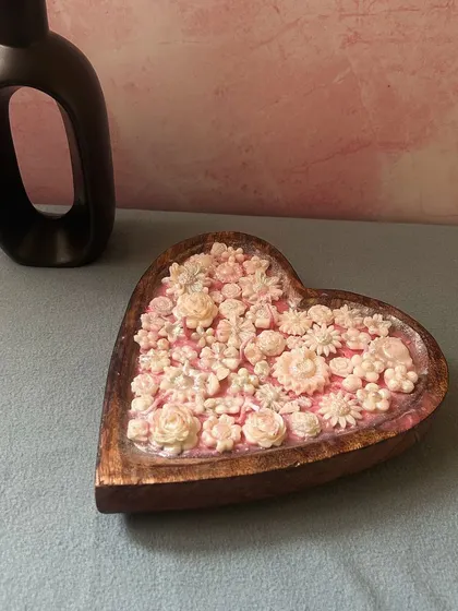 A beautiful close-up of my heart-shaped dough bowl candle, filled with delicate pink and white wax flowers.