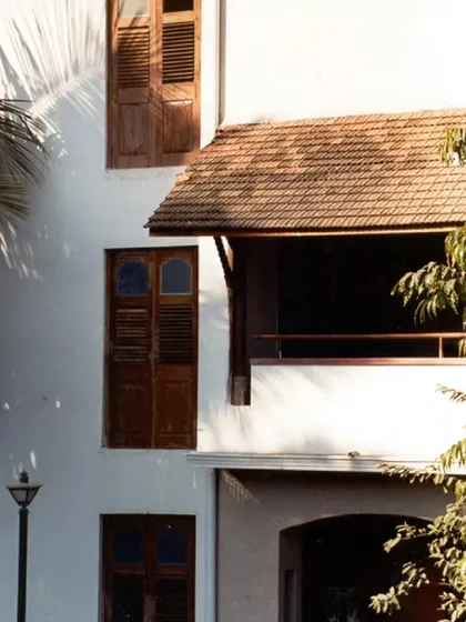 A close-up of the wooden louvered shutters and tiled roof overhang at the Ayushakti resort, details that respond to Mumbai's tropical climate.