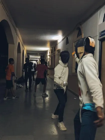 Two fencers spar while others observe in the background. Every moment at the camp is a learning opportunity, whether you are fencing or watching.
