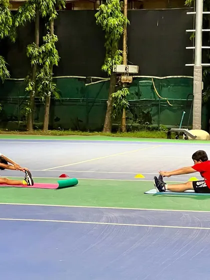Two of our young athletes perform seated stretches after practice. We teach our players the importance of a complete routine, including proper cool-downs, to maintain their bodies and prevent injuries.