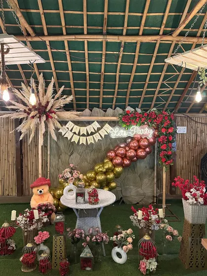 We love a rustic birthday theme. This setup at Sarpanch Bagh in Noida features a "Lets Party" neon sign, a mix of red and gold balloons, pampas grass arrangements, and plenty of floral details for a warm and festive feel.