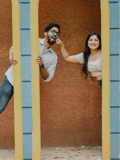 A quirky and fun shot of a couple peeking through yellow bars, their playful personalities shining through.