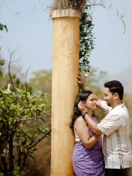 An intimate moment shared between ancient-looking pillars. The warm sunlight and classic architecture create a timeless and romantic setting.