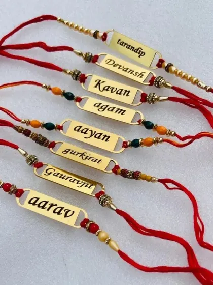 A set of beautiful name-engraved metal rakhis with colorful threads and beads.