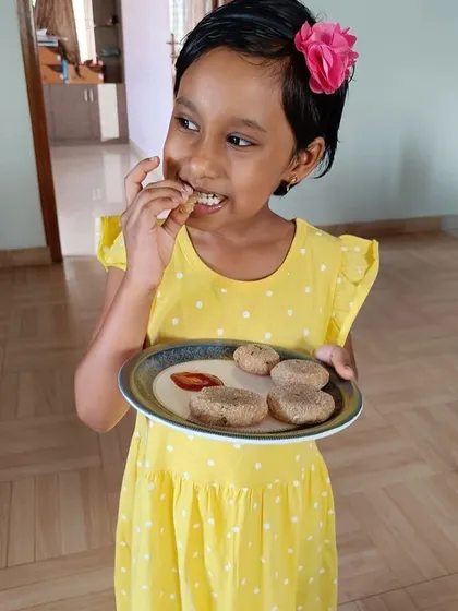 A smiling girl enjoys the food she prepared. The joy of eating something you made yourself is a powerful motivator and a memorable part of our practical life curriculum.
