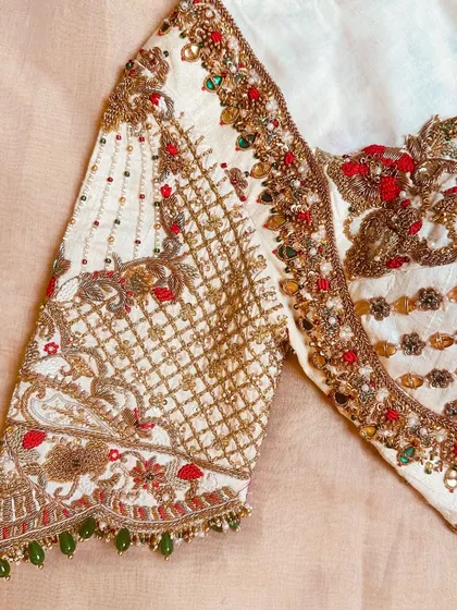 This blouse features delicately crafted peacock cut work on the sleeves and a hand-embroidered border in zardosi and kundan.