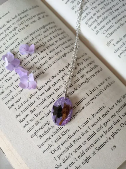 I also create wearable jewelry, like this custom resin pendant. It features a rare Neelakurinji flower preserved against a sparkling lavender background, hanging from a simple silver chain.