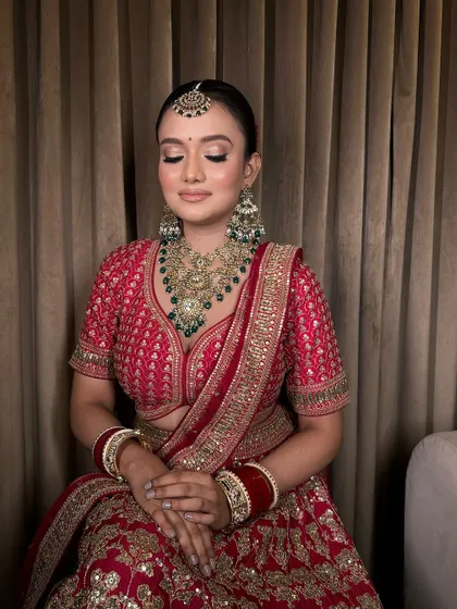 A serene shot of our bride, showcasing the intricate design of her temple jewellery necklace against her red lehenga.