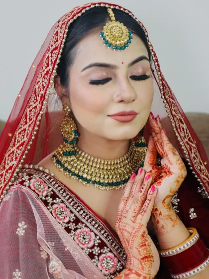 A serene pose with hands joined, showing the intricate mehndi and the beautiful makeup.