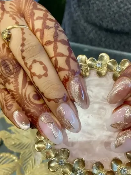 A detailed shot of the gold leaf nail art, showing how the metallic sheen complements the warm tones of the henna.