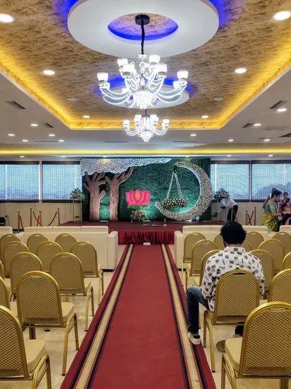 A unique stage with a green hedge wall, a floral moon cradle, and tree cutouts.