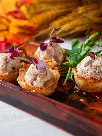 Close-up of our savory tartlets filled with a creamy mixture and topped with microgreens. These bite-sized appetizers are perfect for cocktail hours and networking events.