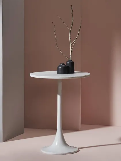 A minimalist white tulip table styled with small, dark vases. The use of geometric shapes and contrasting colors creates a modern and sophisticated product shot.
