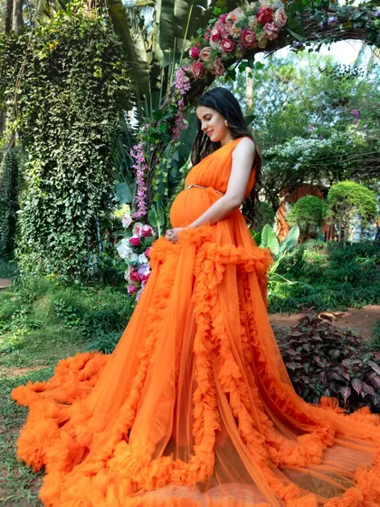This is the kind of magical, fairy tale moment we love to create. This beautiful mom-to-be is glowing in one of our vibrant orange tulle gowns, surrounded by the lush greenery of a Bengaluru garden.