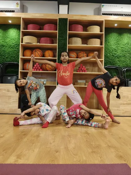 A beautiful group pose demonstrating balance, flexibility, and cooperation. Partner and group activities are a core part of our kids' yoga, teaching them to work together.