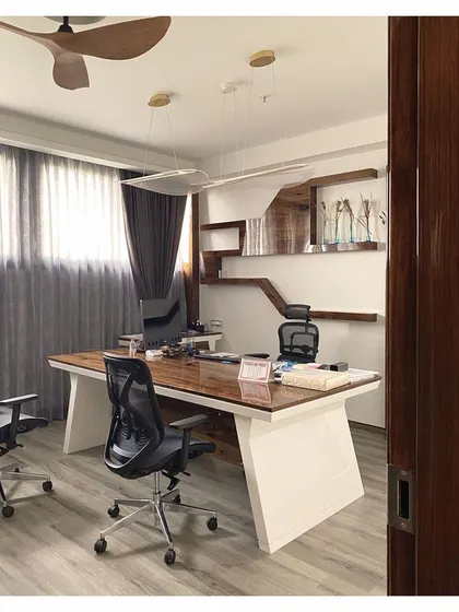 A close-up of another executive office, showcasing a large desk with a white base and wood top. The modern pendant light and custom shelving demonstrate our ability to create personalized and functional cabins.