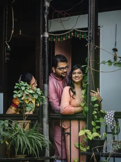A candid moment captured through the balcony railings, with a family member peeking through the plants. It tells a story of a home filled with love and fun.
