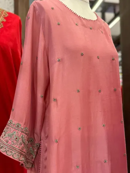 A close-up of a soft pink silk kurta with delicate buti embroidery and detailed work on the cuffs.