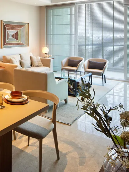 An open-plan living and dining area where a neutral color palette creates a calm and cohesive feel. The large windows and sheer blinds allow for soft, diffused natural light, making the space feel bright and airy.