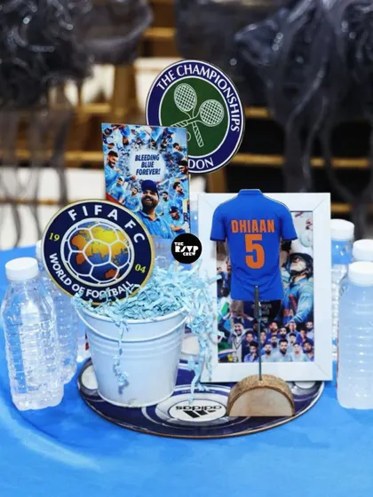 A sports-themed table centerpiece featuring logos from FIFA and Wimbledon, along with a framed photo of the birthday boy in his jersey.