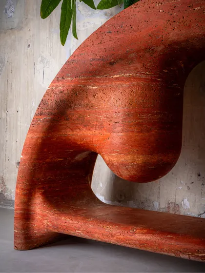 Craftsmanship is in the details. This is a close-up of the Samaveta Console, carved from a single piece of red travertine. The fluid, sculptural lines and the raw, natural texture of the stone come together to create a piece that is both powerful and elegant.