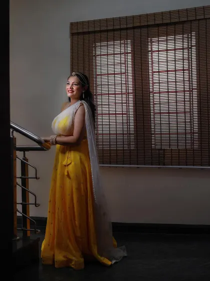 Our bride Dhruthi looking like a doll ('Gombe') in her yellow Haldi lehenga. The soft lighting and her serene smile make for a beautiful portrait.