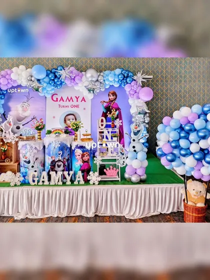 A closer view of the Frozen party setup, highlighting the balloon arch in shades of blue, purple, and silver.