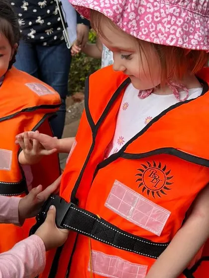A child tries on a life vest, learning about different types of safety equipment used by community helpers.