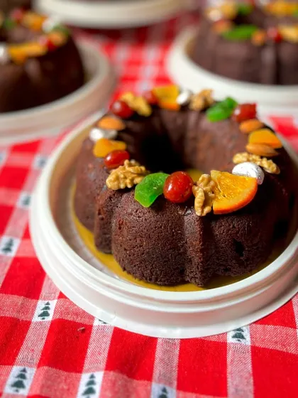 A fruit-and-nut-topped plum cake appears in our Christmas range, with a bundt shape and seasonal colours around the plate.