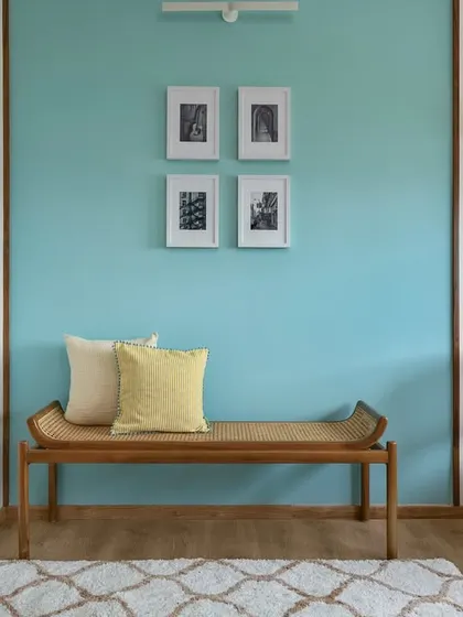 The home office in our 'Malhar' project features a serene blue accent wall, a comfortable cane bench, and a matching chair. The space is designed to be both calming and inspiring.