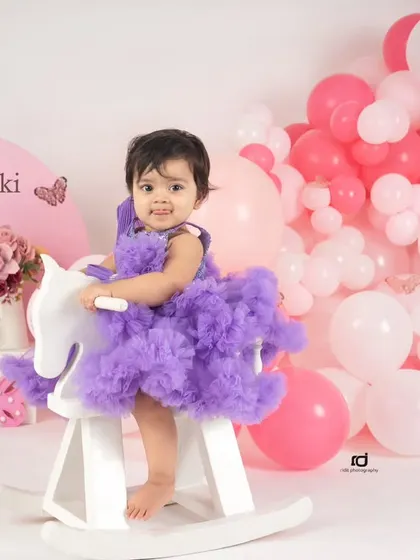 Dressed in a fluffy purple tutu, this birthday girl looks adorable on her white rocking horse. It's a sweet and playful portrait to mark her first year.