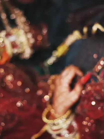 An artistic, high-angle shot of the bride. The focus is on her expressive eyes and the beautiful details of her henna and jewelry, with a soft, blurry background.