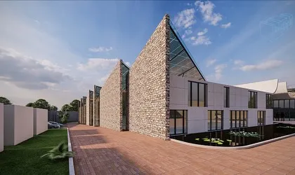 An alternate view of the textile mill's exterior, showcasing the sawtooth roofline with integrated solar cells and walls clad in stone. The design balances industrial requirements with a strong, natural aesthetic.