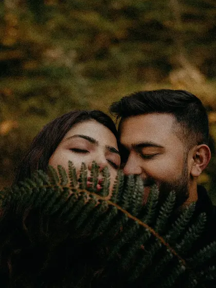 A creative close-up of a couple seen through a fern leaf, their eyes closed in a moment of quiet intimacy. This shot uses natural elements to frame a beautiful, personal moment during a hill station pre-wedding shoot.