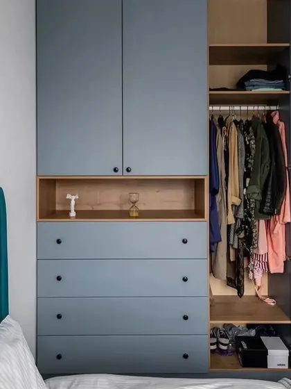 This hinged wardrobe in a matte blue finish includes an open wooden niche for display. The image shows the internal configuration with hanging space and shelving.