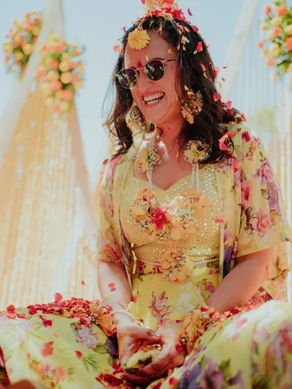 The bride is glowing with happiness as she is showered with petals during her Haldi. It's the perfect start to the wedding celebrations.