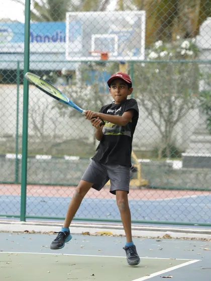 A young athlete in our program prepares to hit a two-handed backhand. We provide coaching on all strokes, ensuring a well-rounded development of skills for our junior players.