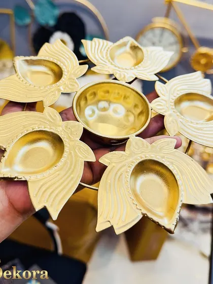 A handheld view of our metal diya stand, featuring five lotus-shaped diyas surrounding a central bowl. Its compact and elegant design makes it a popular choice for employee gifts.