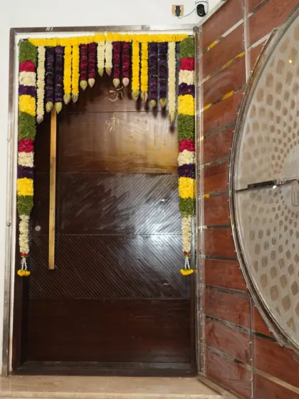 The main door of a home decorated with traditional flower garlands for a housewarming ceremony.