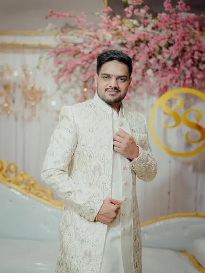 A stylish shot of the groom adjusting his sherwani. The angle and pose give this portrait a confident and modern feel, capturing his personality.