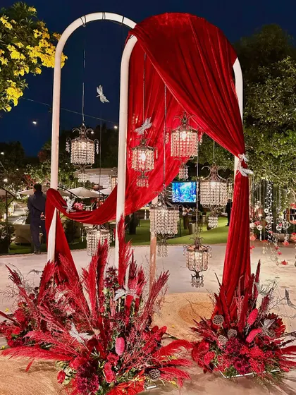 A stunning entrance arch for a cocktail party, draped in red velvet and adorned with crystal lanterns.