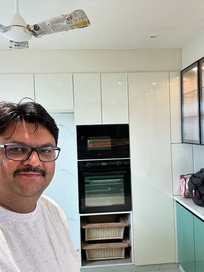Here I am on-site with a nearly finished kitchen, featuring a tall unit with a built-in oven and microwave. We ensure every appliance fits perfectly into our custom modular designs.
