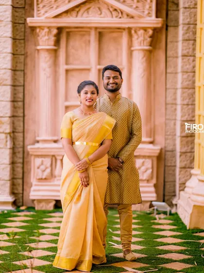 An elegant portrait of a couple in matching traditional wear. The simple, classic pose and the beautiful architecture create a timeless pre-wedding photo.